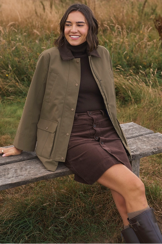 Femme portant une veste marron, un pull à col roulé et une jupe en velours côtelé en plein air