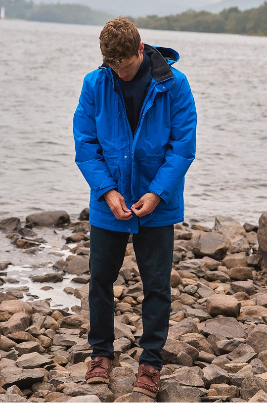 Homme portant une veste de pluie imperméable et un pantalon au bord d'un lac